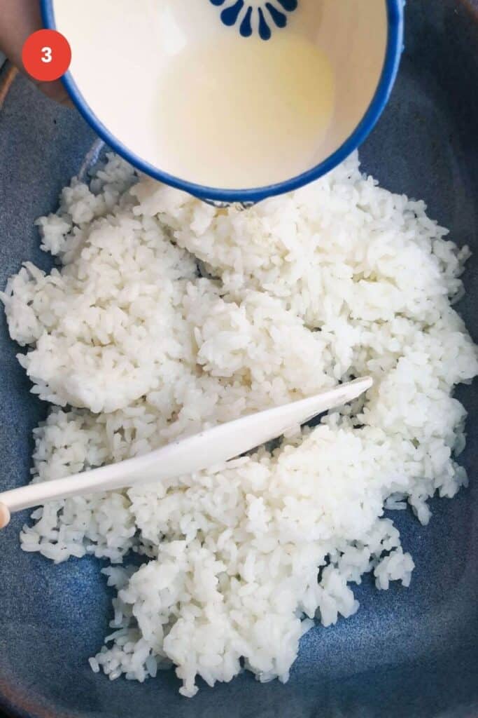 Mixing rice vinegar through sushi rice.