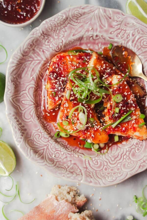 Four wedges of sweet chilli haloumi on a pink plate with more sweet chilli on the side.