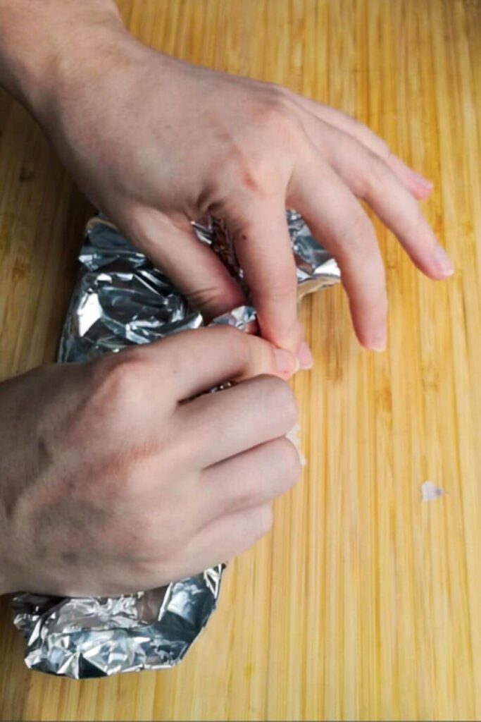 Two hands wrapping up a baking foil package.