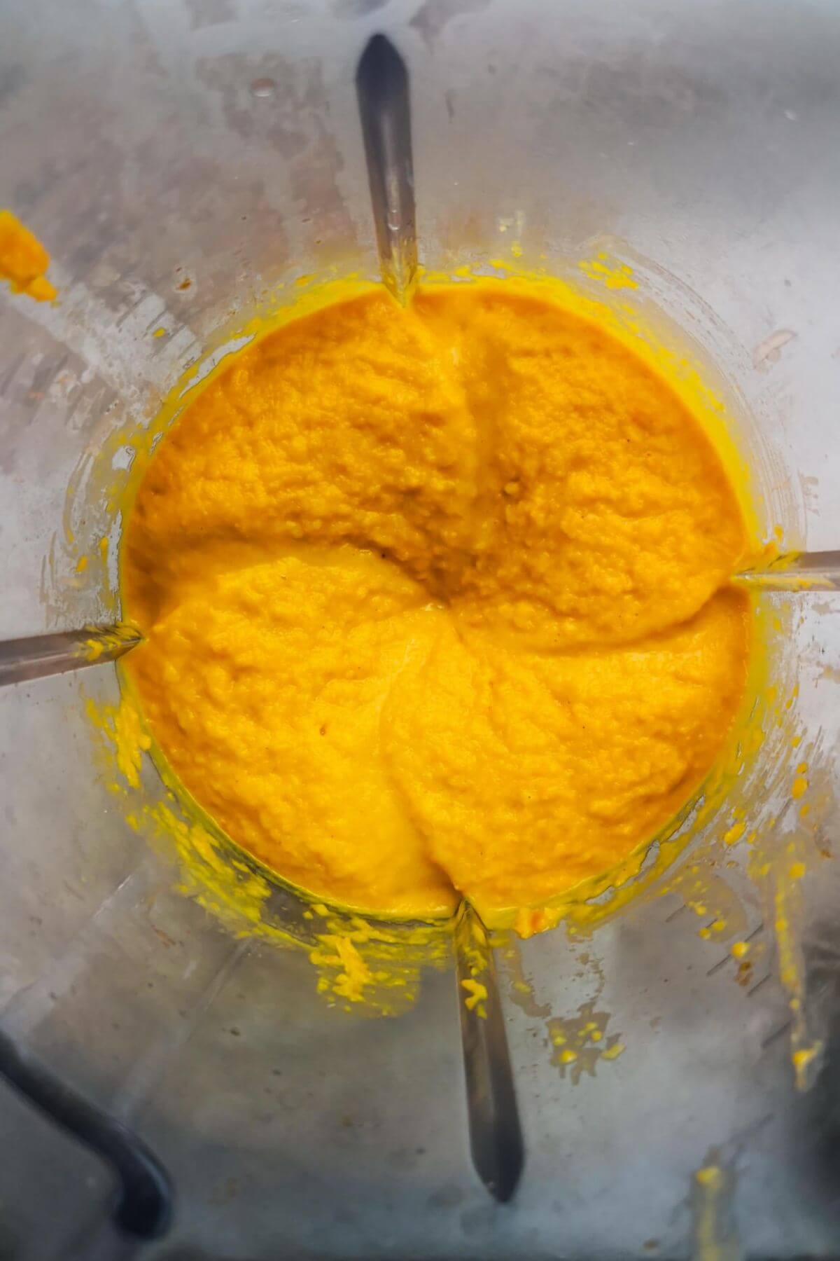 Looking down on whipped carrot dip in the bowl of a blender.