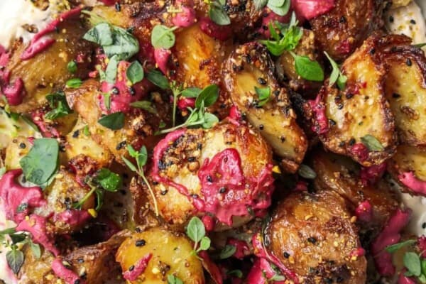 Crispy dukkah potatoes on a bed of aioli with thyme and pink tahini scattered on top.
