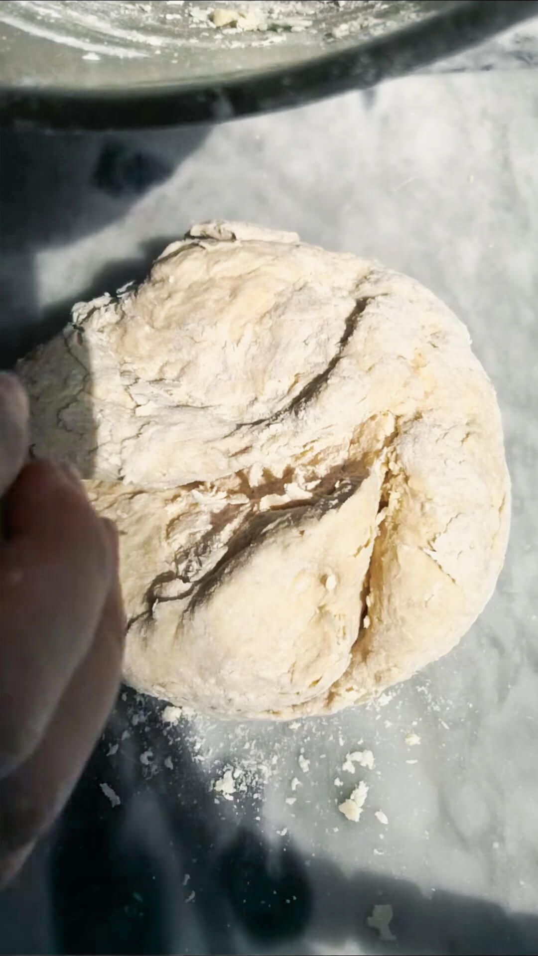 Floury, rough dough on a grey marble surface.