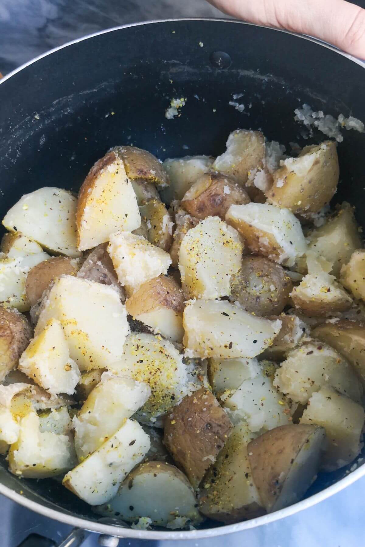 Fluffed up chopped potatoes in a black pot with dukkah tossed through.