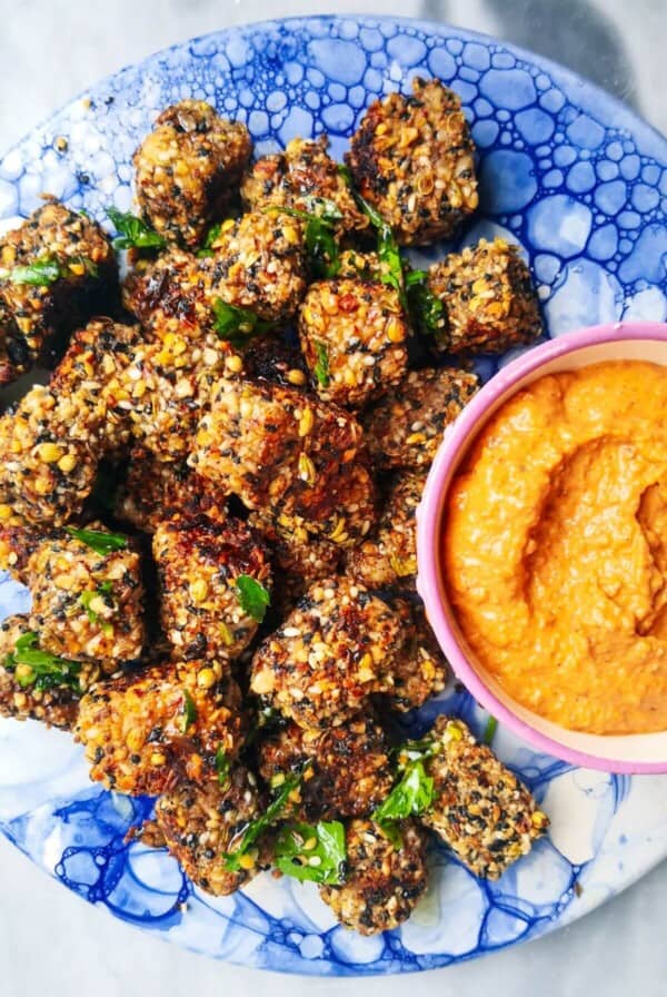 Halloumi bites on a blue marble plate with red pepper sauce on the side.