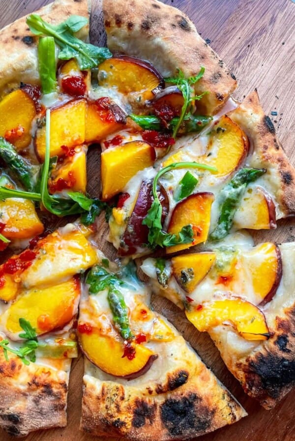 Peach blue cheese pizza sliced on a wooden board.