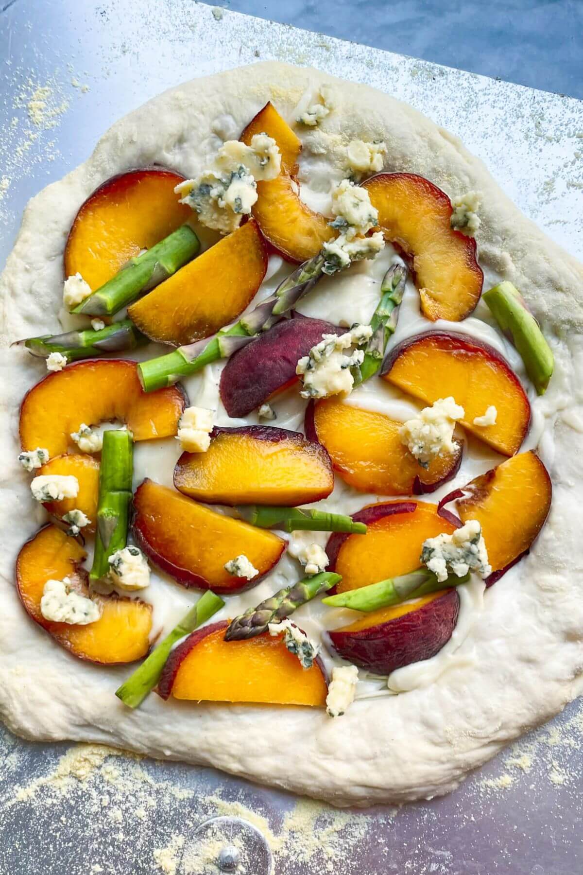 Peach, asparagus, blue cheese pizza ready to go into the oven.