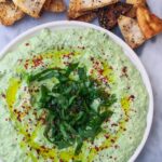 Spinach and feta dip on a small white plate with pita chips.