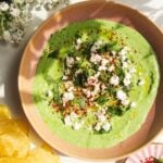 Spinach and feta dip in a pink bowl with chips on the side.