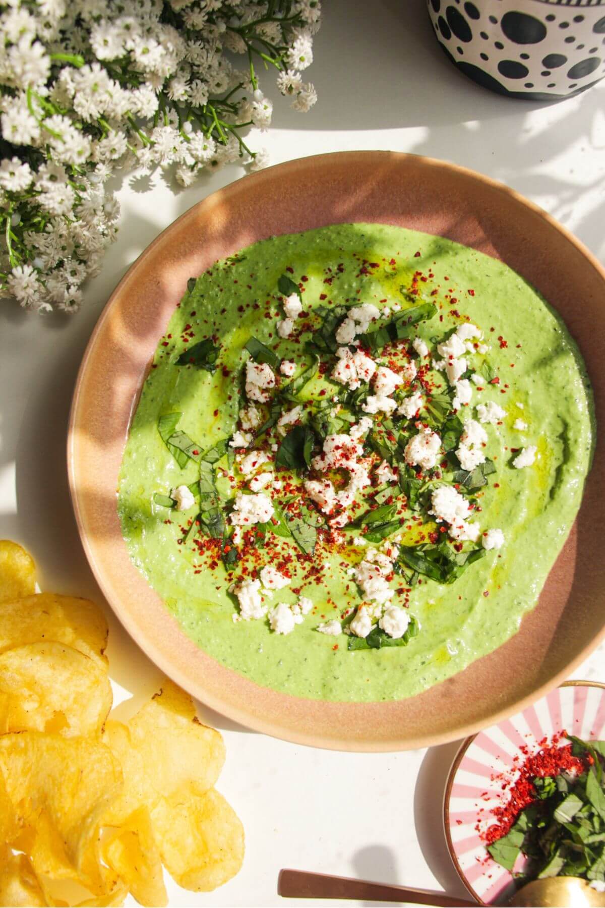 Spinach and feta dip in a pink bowl with chips on the side.