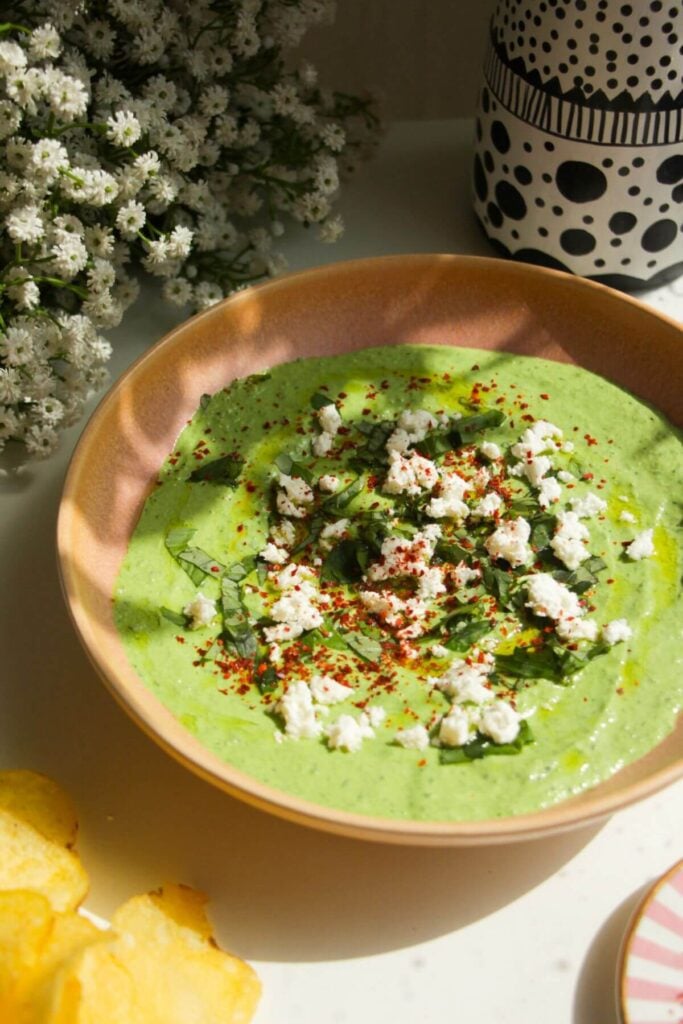 Spinach and feta dip in a pink bowl with chips on the side.