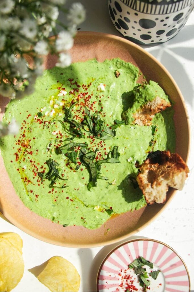 Spinach and feta dip in a pink bowl with chips on the side.