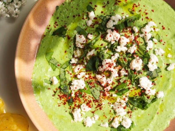Spinach and feta dip in a pink bowl with chips on the side.
