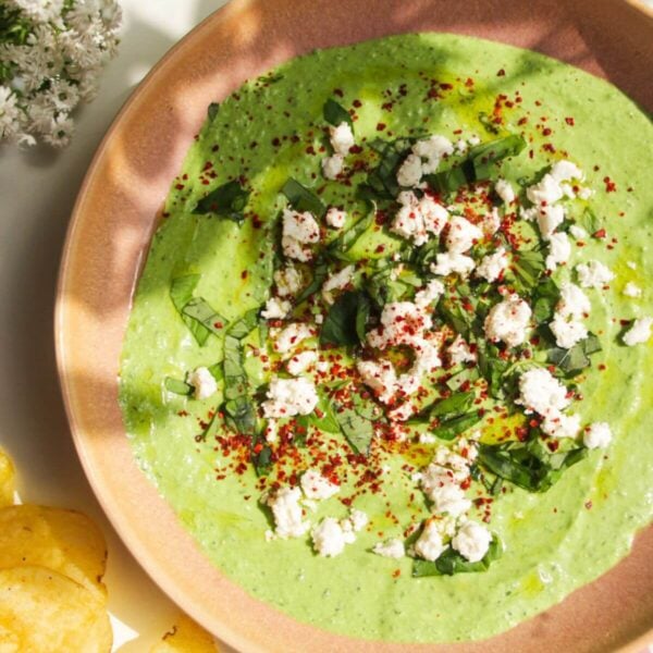 Spinach and feta dip in a pink bowl with chips on the side.