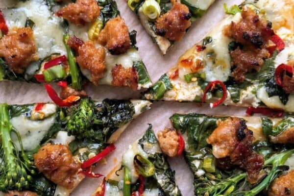 Whipped ricotta, sausage, broccolini and chilli pizza sliced.