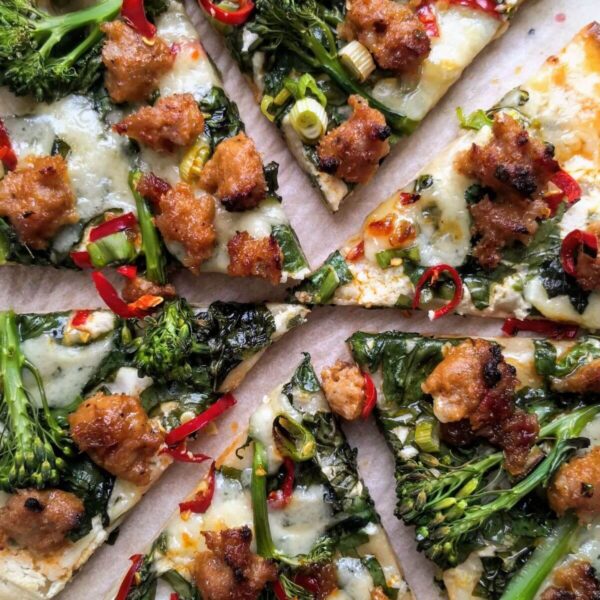 Whipped ricotta, sausage, broccolini and chilli pizza sliced.