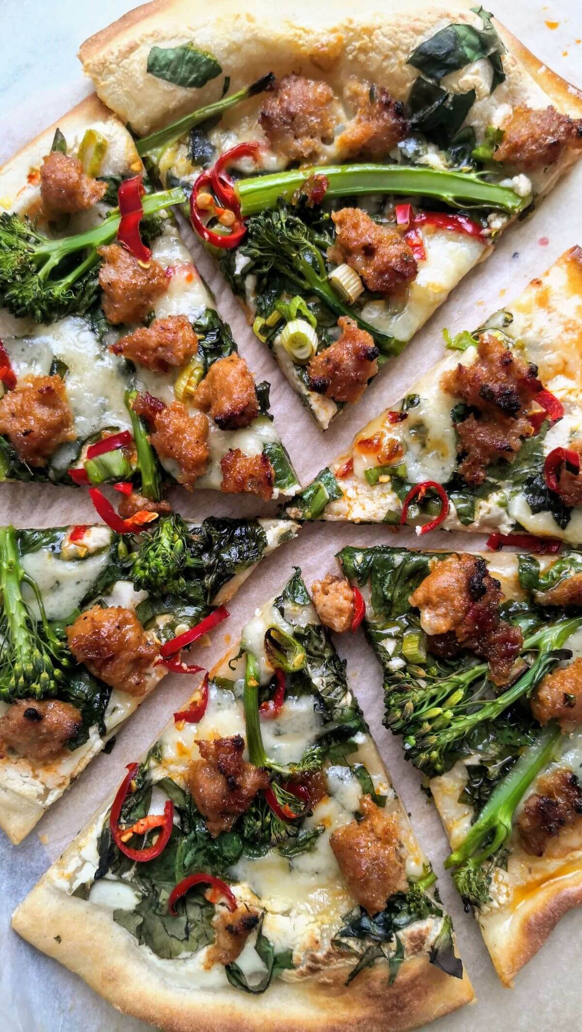 Whipped ricotta, sausage, broccolini and chilli pizza sliced.