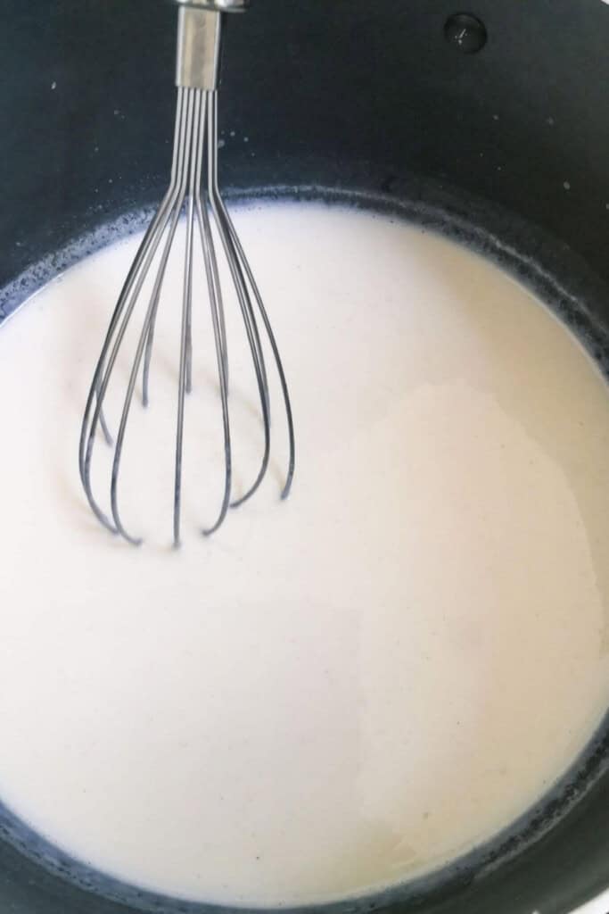 Milk being whisked in a pot.