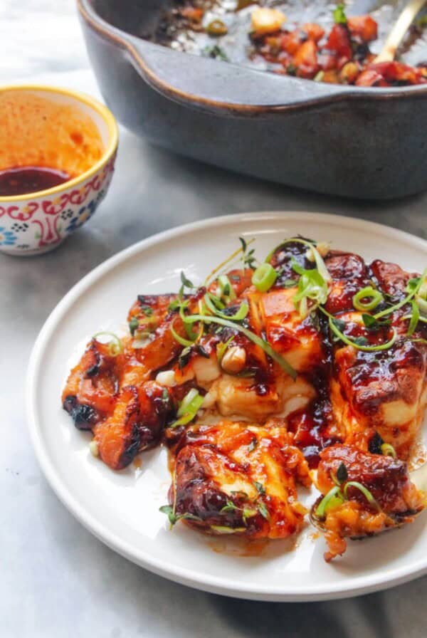 Baked whole halloumi on a small white plate with blue oven dish in the background.