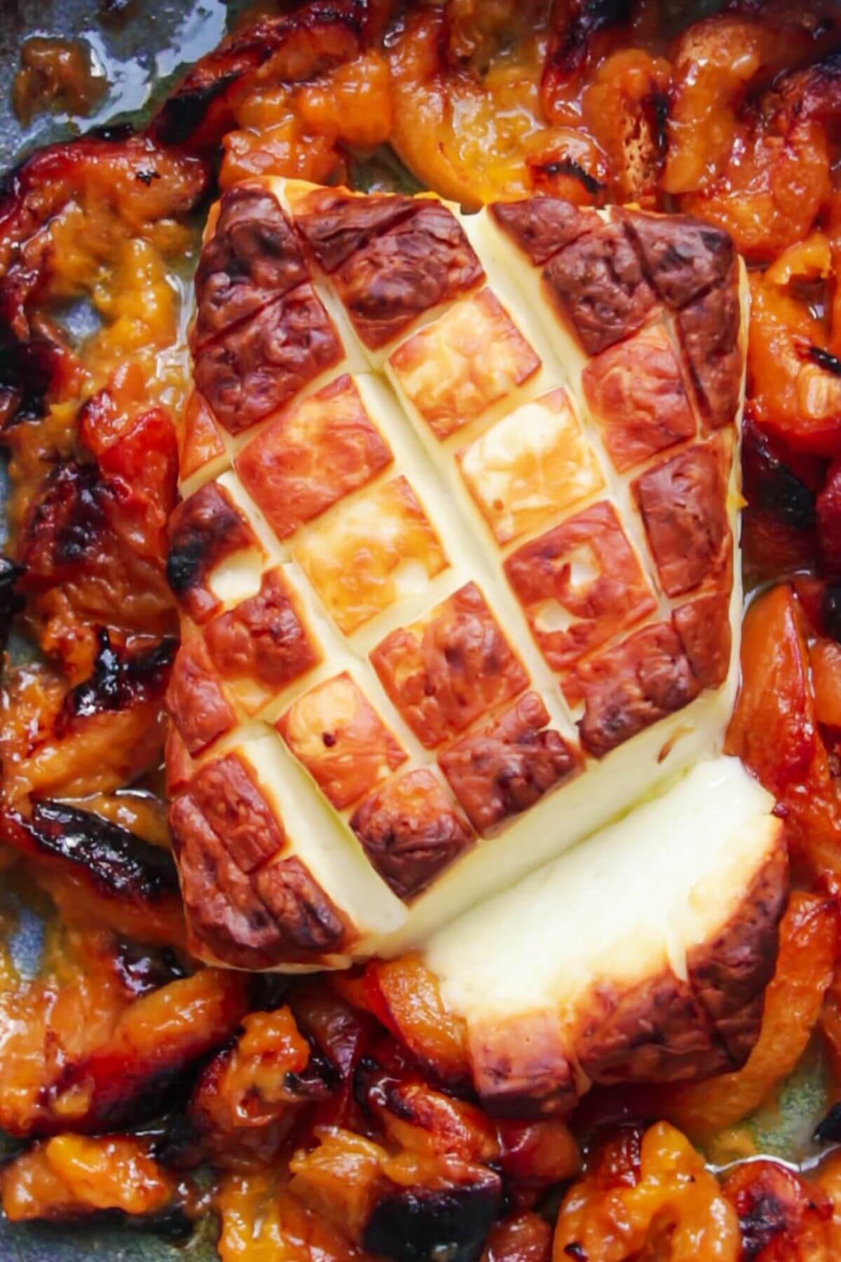 Whole baked halloumi with roasted apricots in a small blue oven dish.