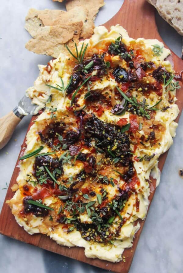 Butter smoothed onto a board and topped with chilli oil, fig chutney and herbs with crackers and bread on the side.