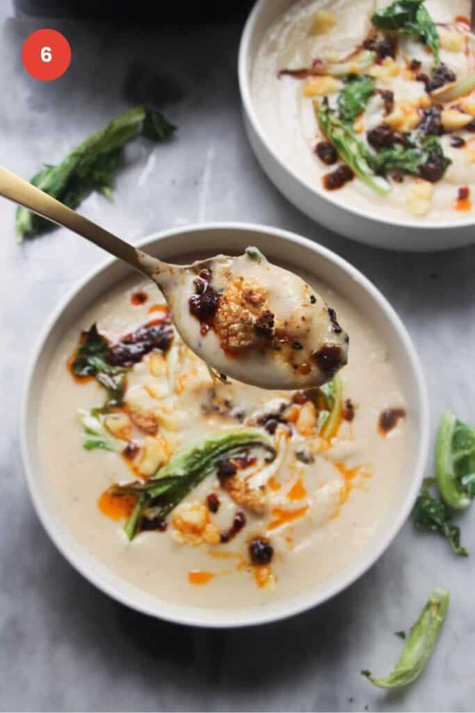 Cauliflower cheese soup in a bowl, topped with chili oil.