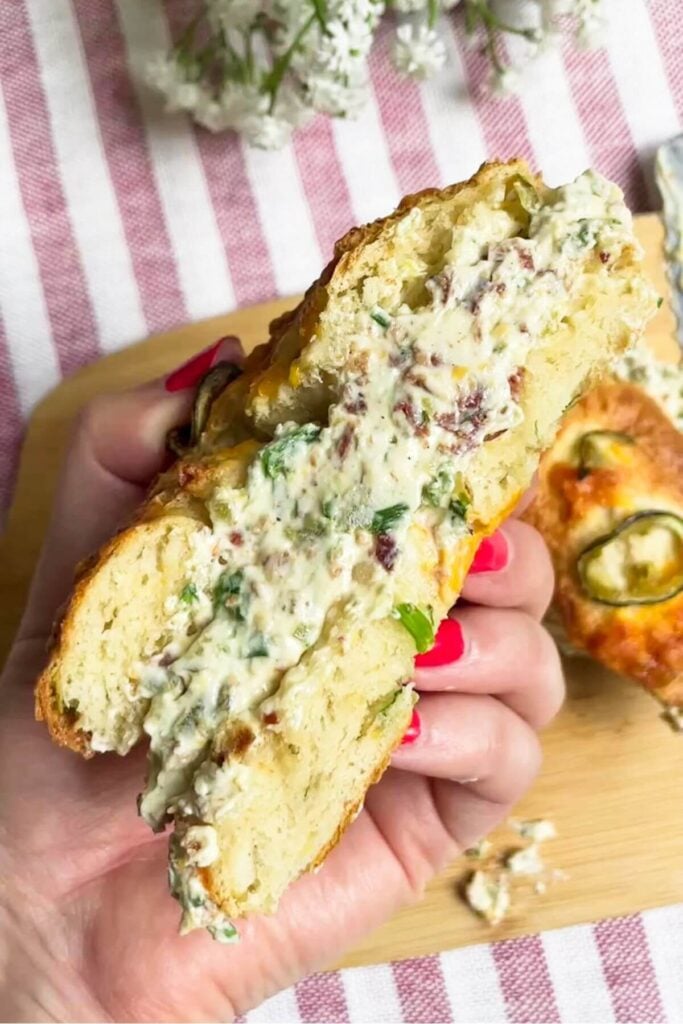 Hand holding a bagel filled with jalapeno popper cream cheese.