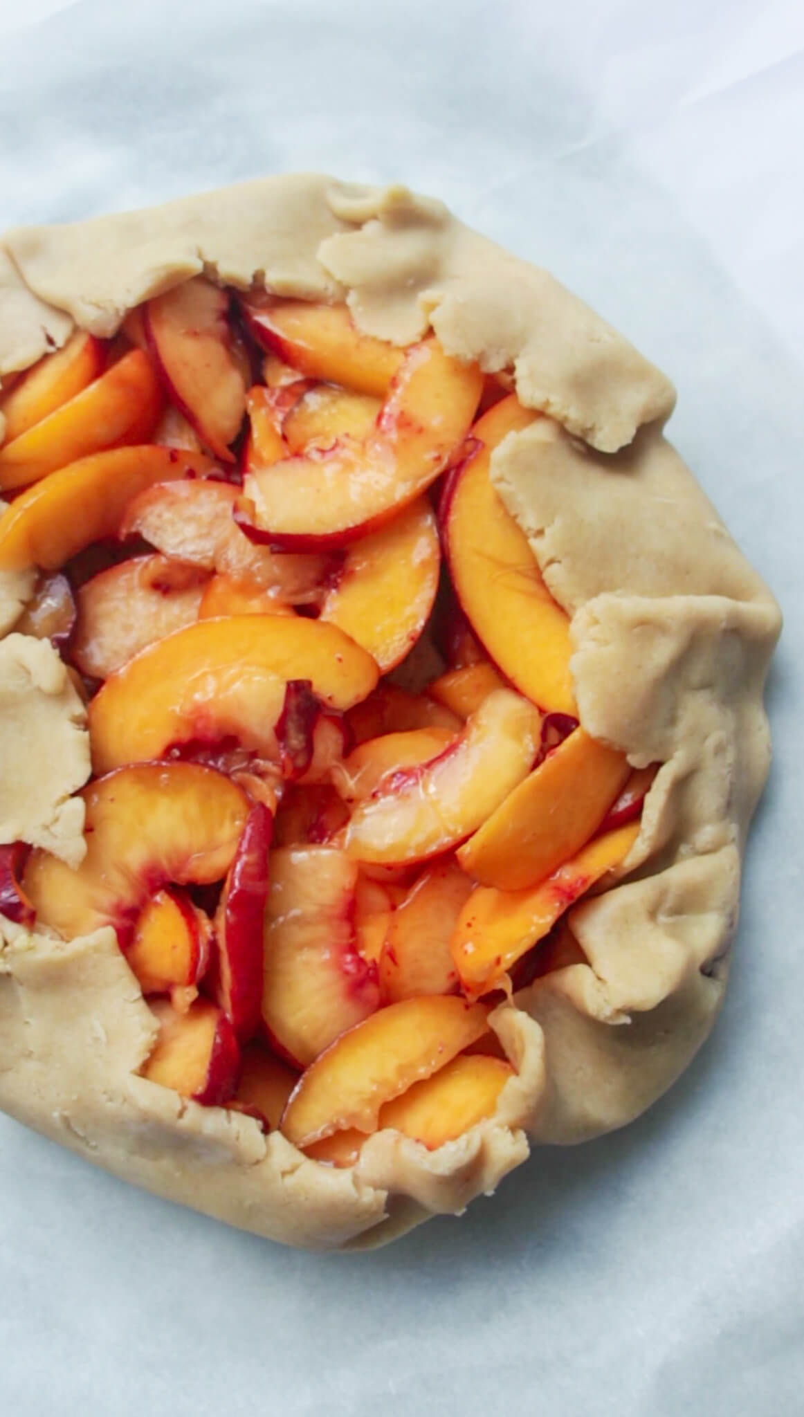 Peach almond galette on baking paper ready to be baked.