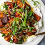 Miso roasted sweet potatoes on labneh, with chilli lime salsa on top on a white plate.