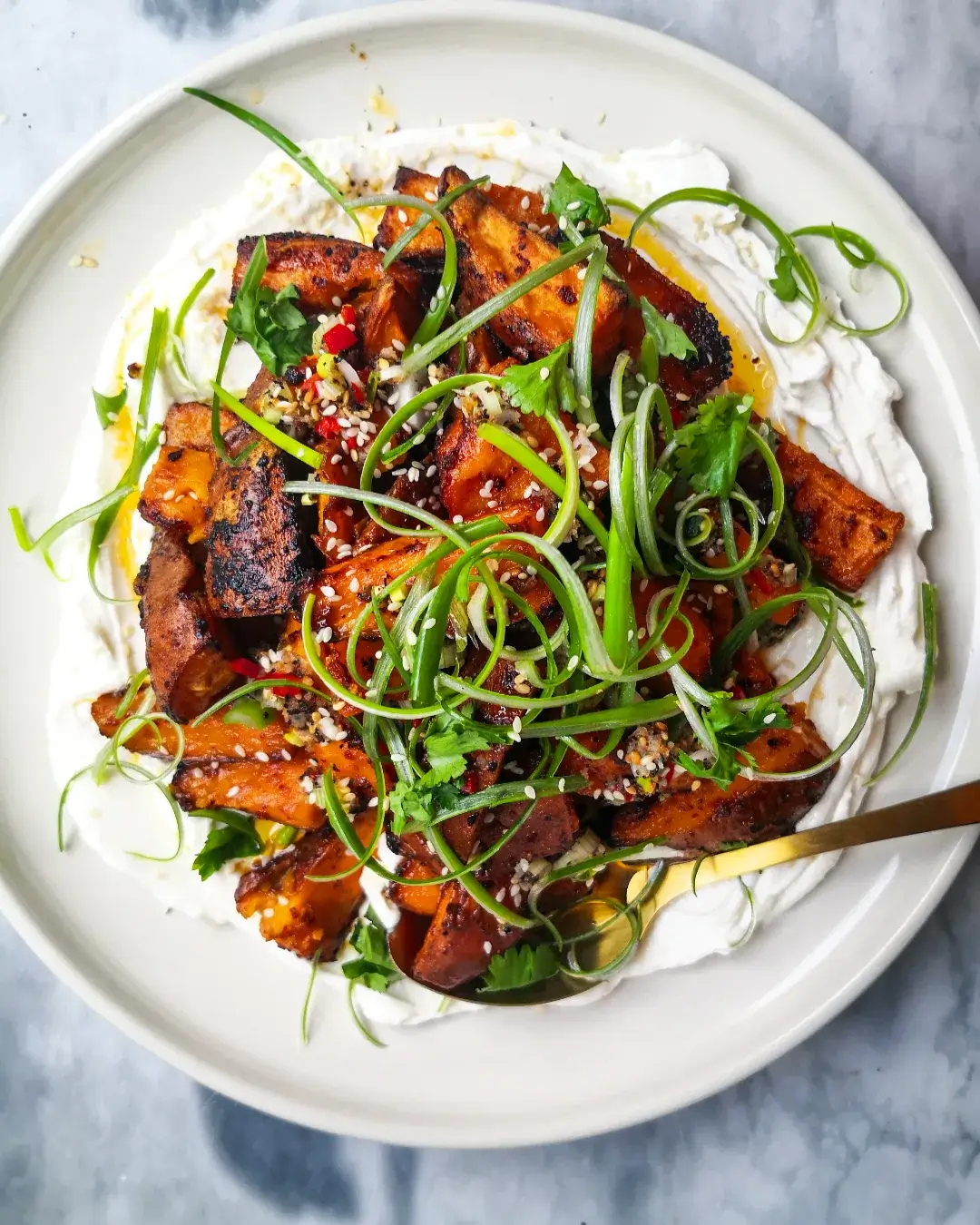 Miso roasted sweet potatoes on labneh, with spring onions and sesame seeds on top.