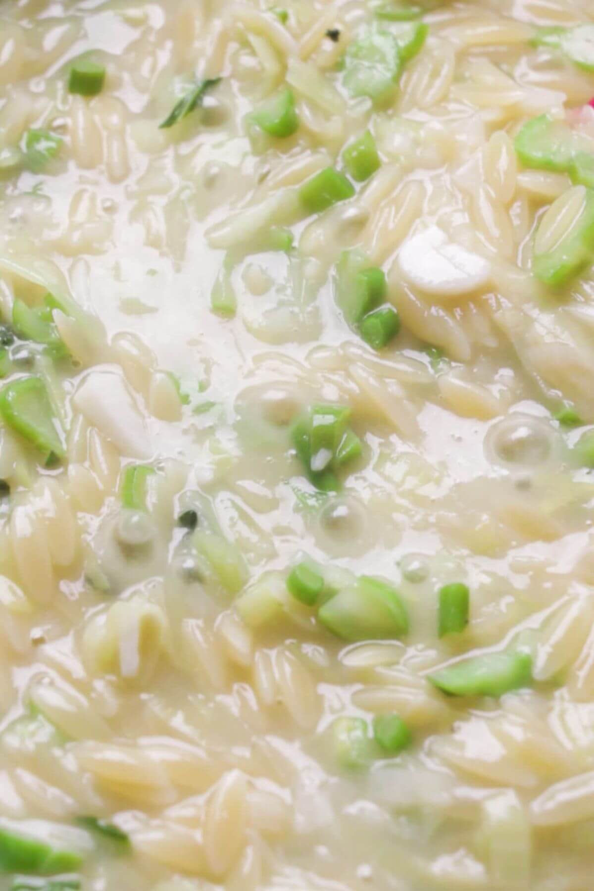 Close up of orzo bubbling in pan.