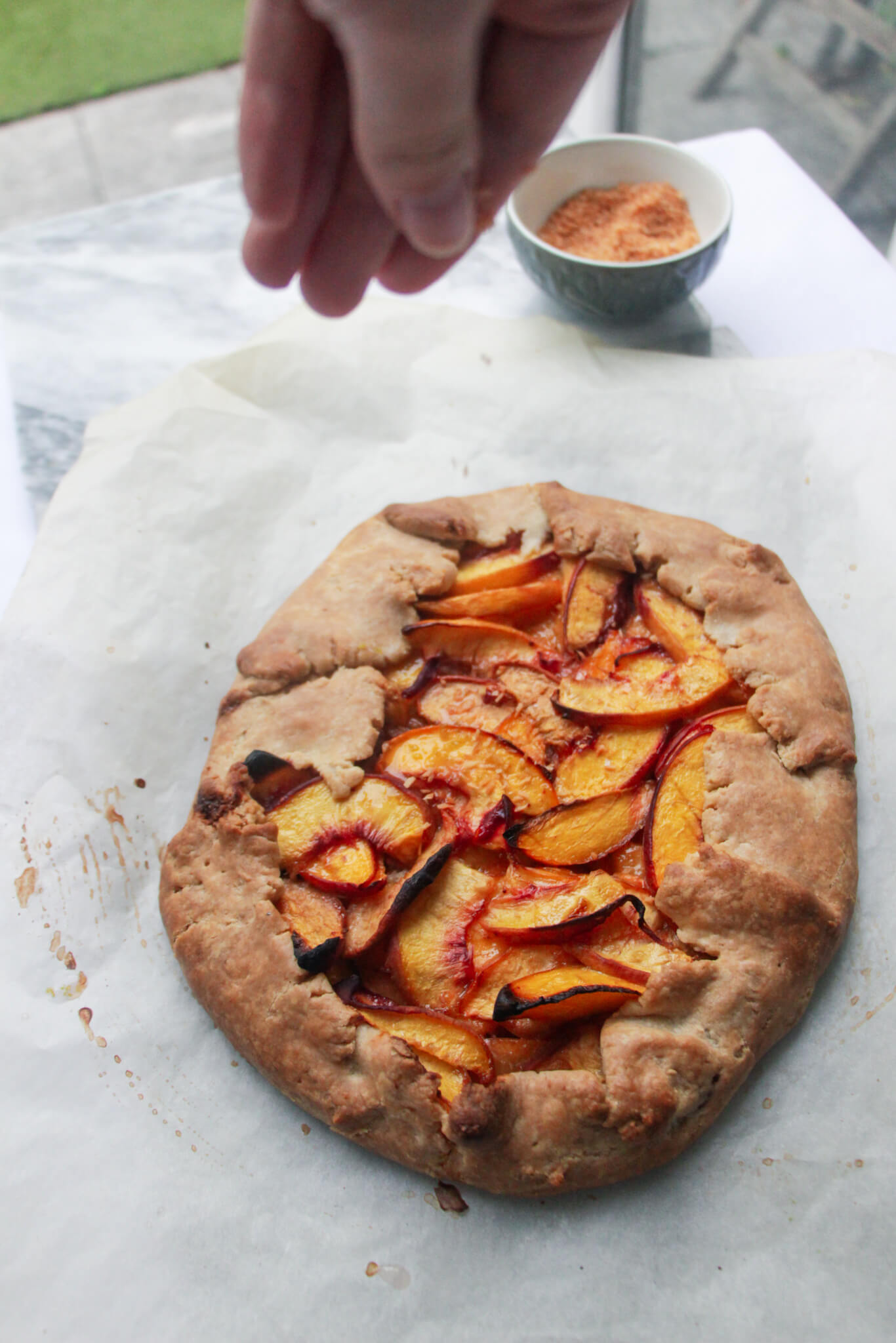 Hand sprinkling toasted coconut over peach galette.