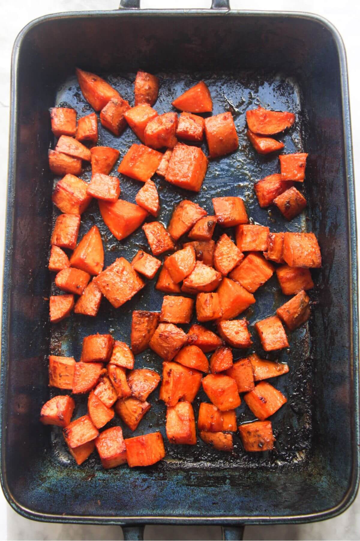Chunks of miso roasted sweet potatoes in a large blue oven dish.