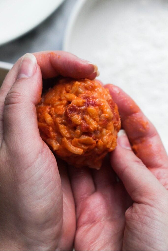 2 hands forming arancini rice ball.
