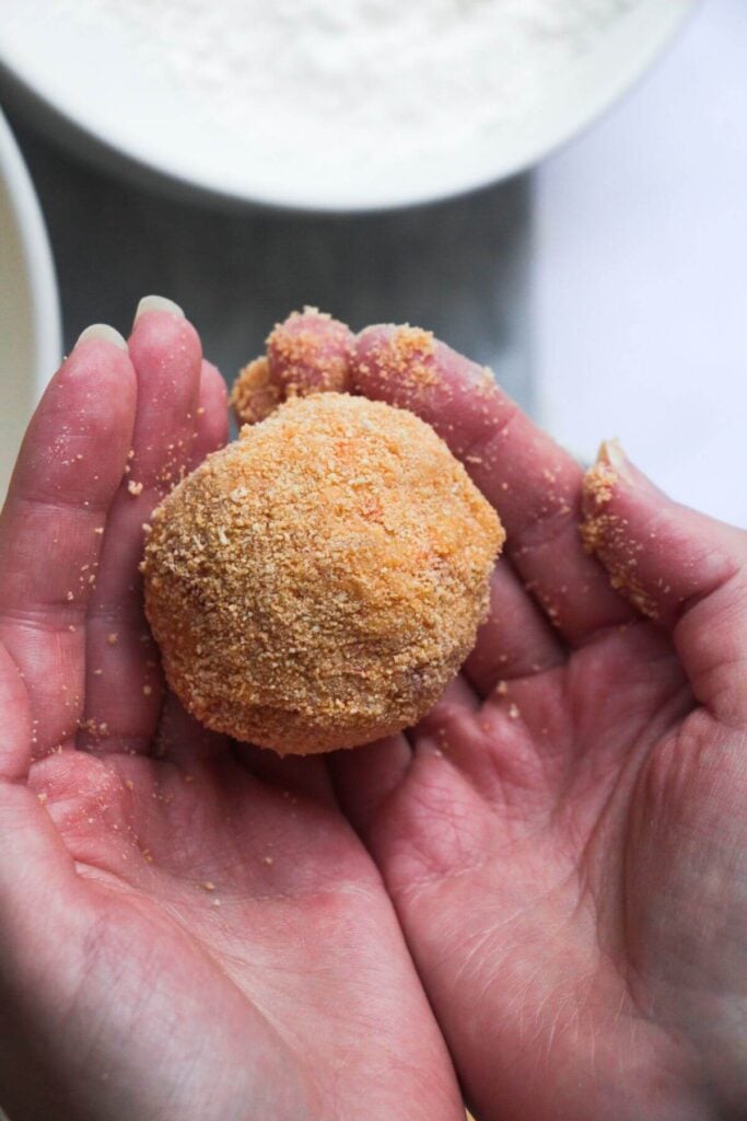Close up of coated arancini ball in hands.