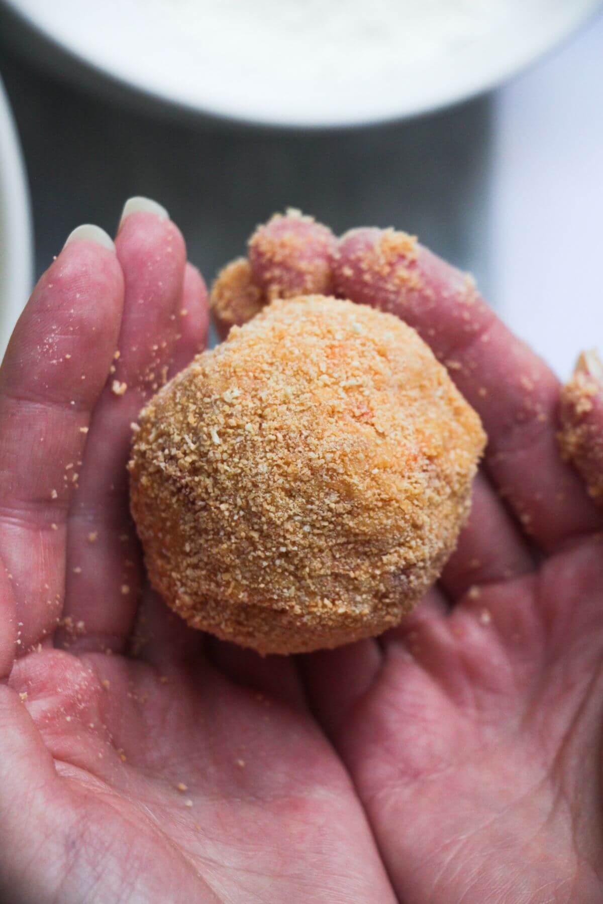 Close up of coated arancini ball in hands.