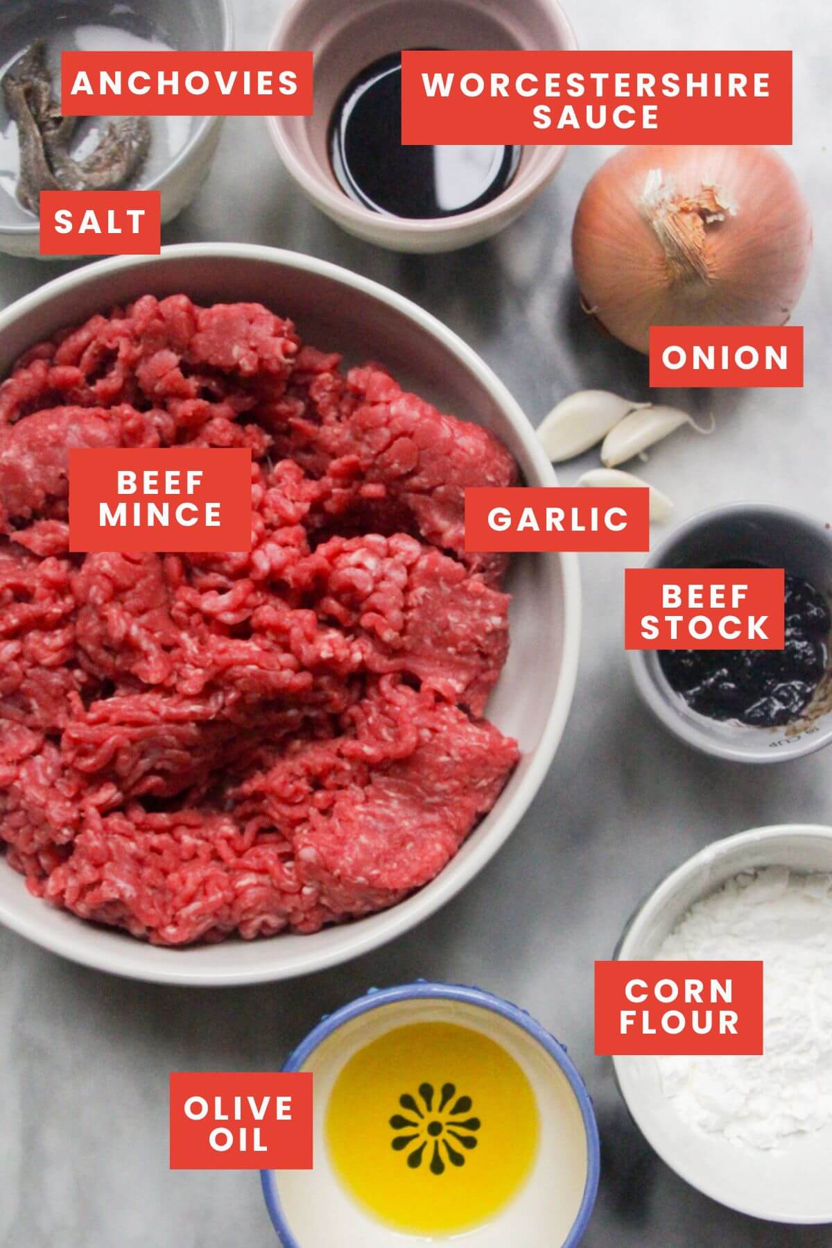 Beef mince filling ingredients laid out on a marble background and labelled.
