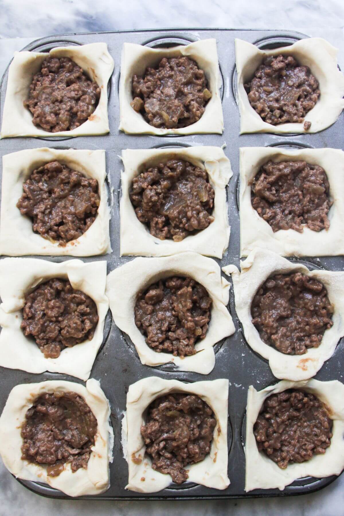 Beef mince inside pastry inside a 12 piece muffin tin.
