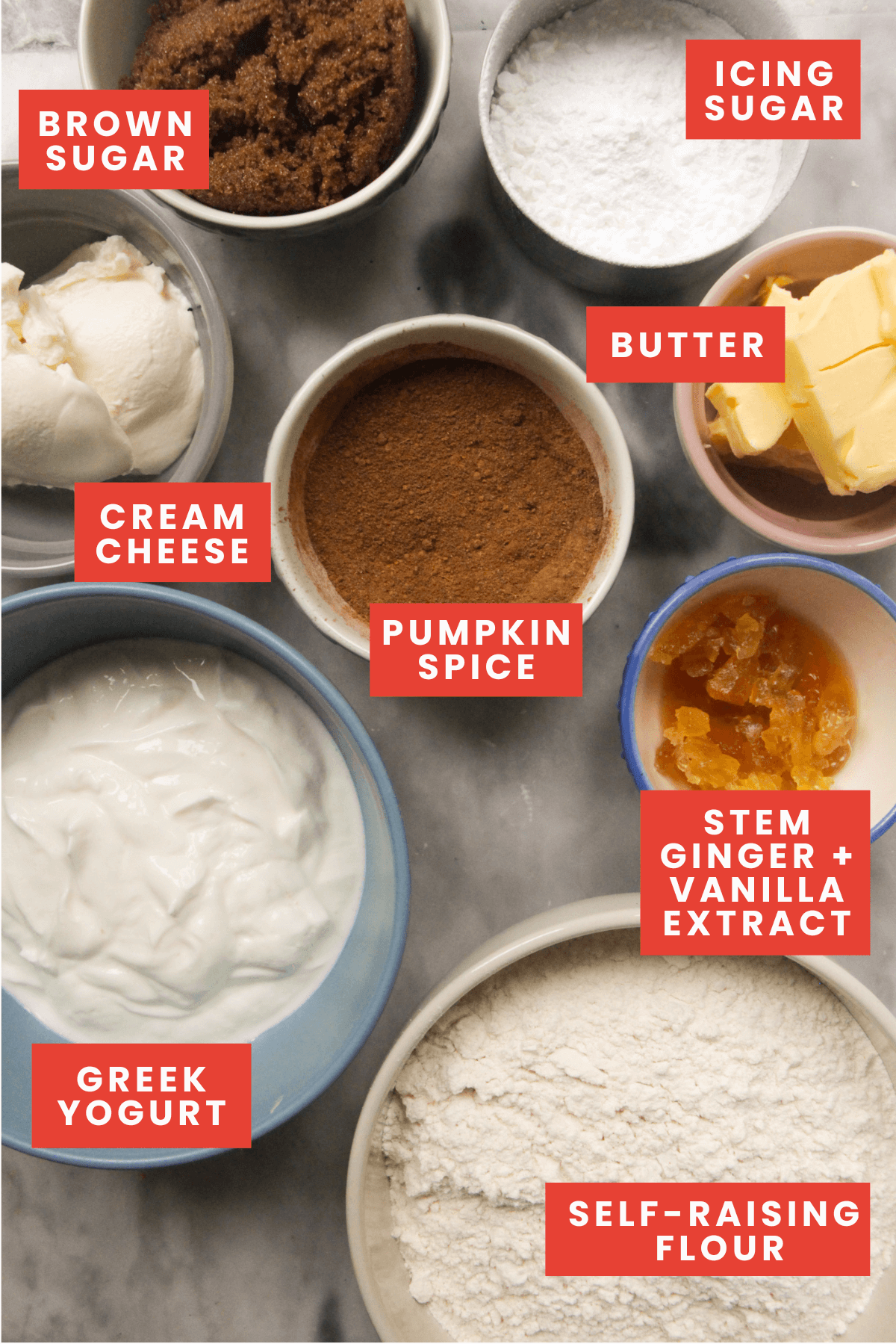 Ingredients for pumpkin spice cinnamon rolls on a marble background and labelled.