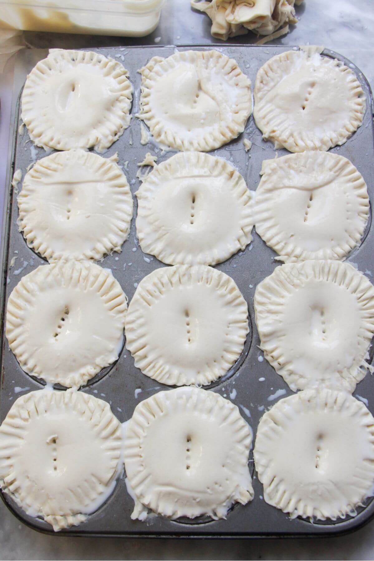 12 mince and cheese pies, sealed and ready to be baked in the oven.