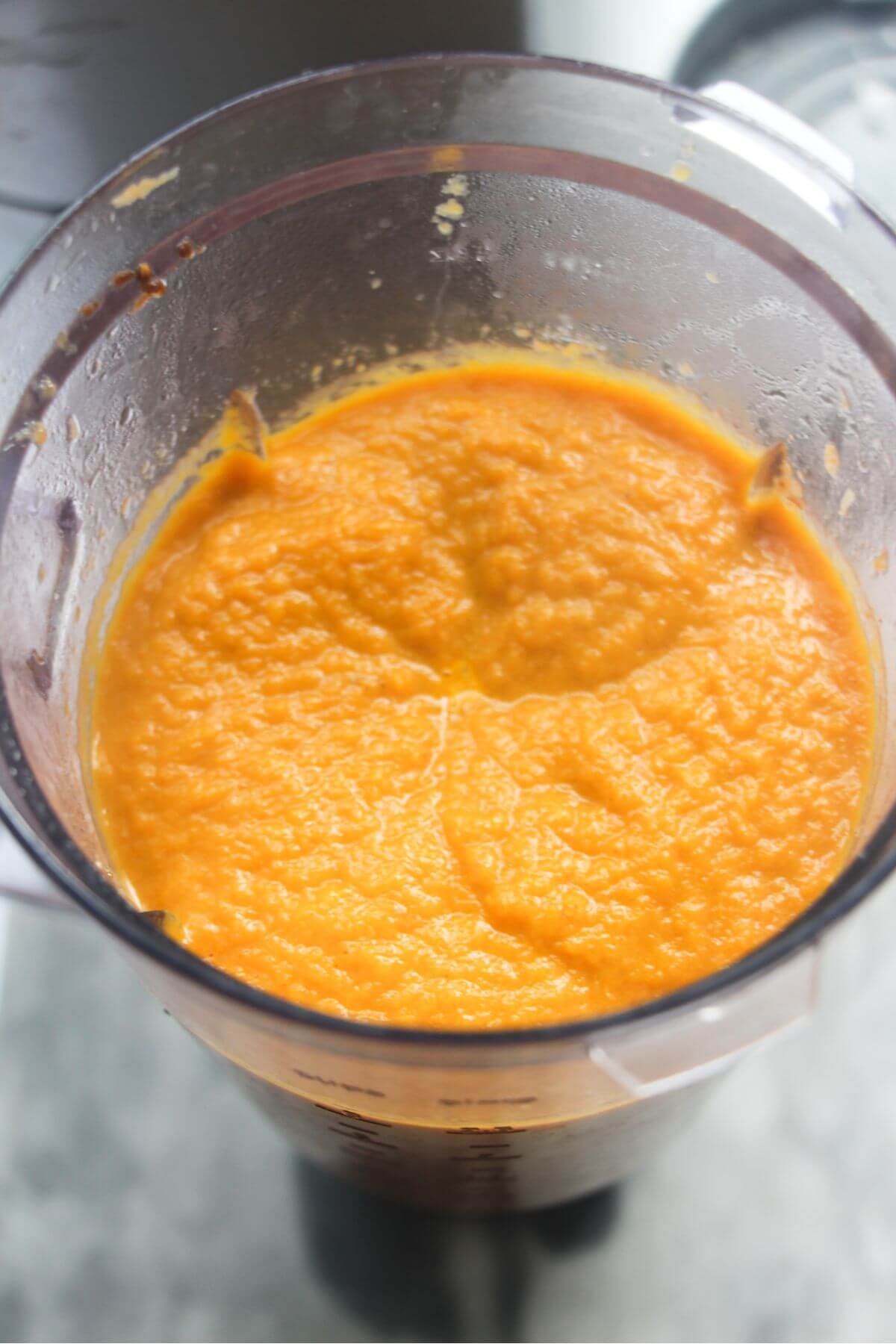 Blended orange carrot soup in a blender, looking down from above.