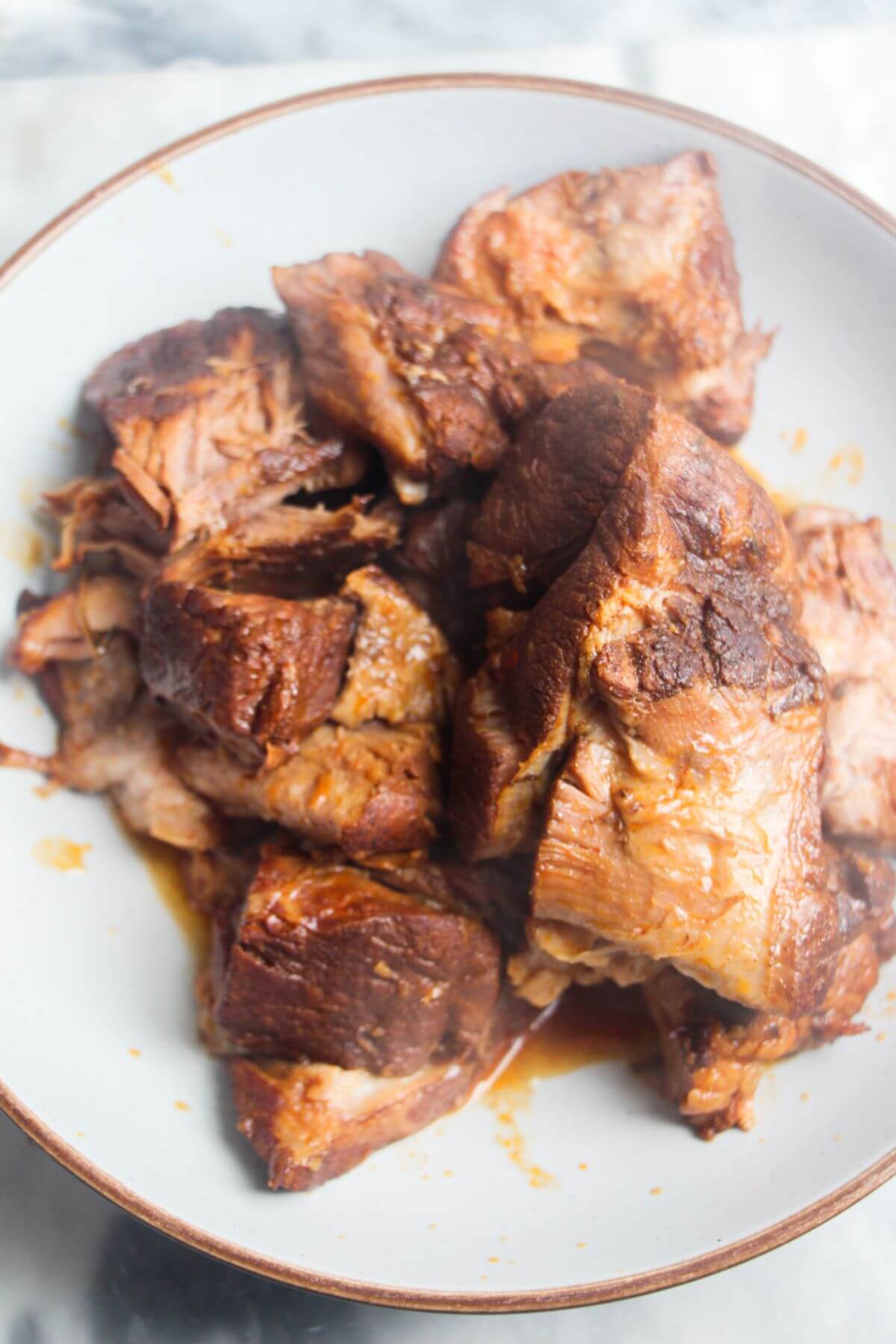 Cooked pieces of pork shoulder in a shallow bowl.