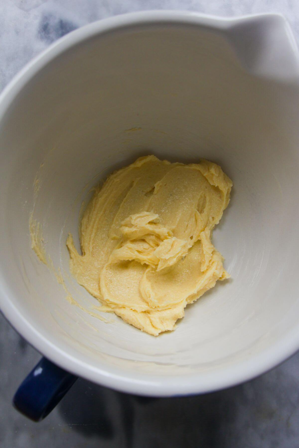 Butter and sugar creamed in a white mixing bowl.