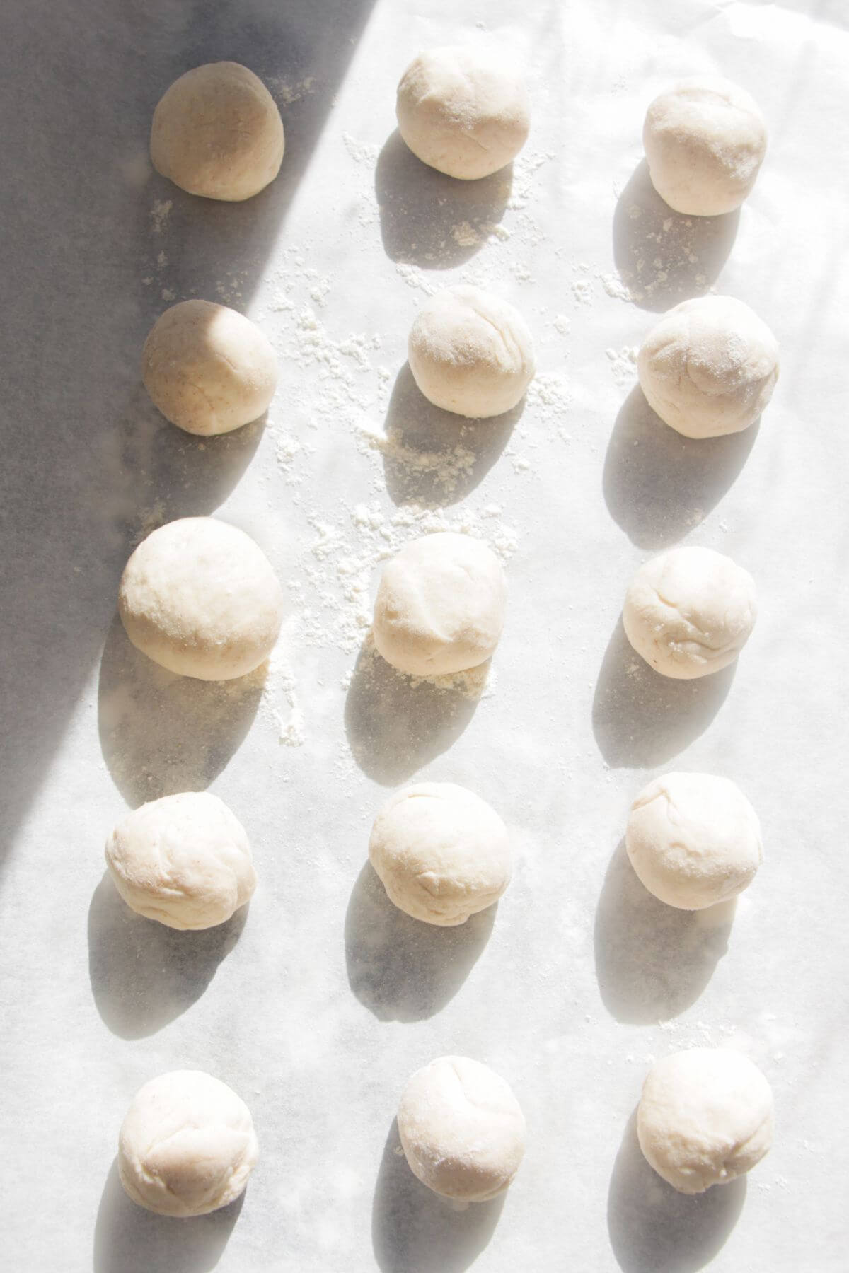 15 dough balls lined up on a grey marble background.