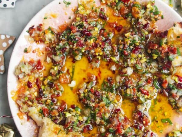 Festive dipping oil in a small pink plate on a grey surface.