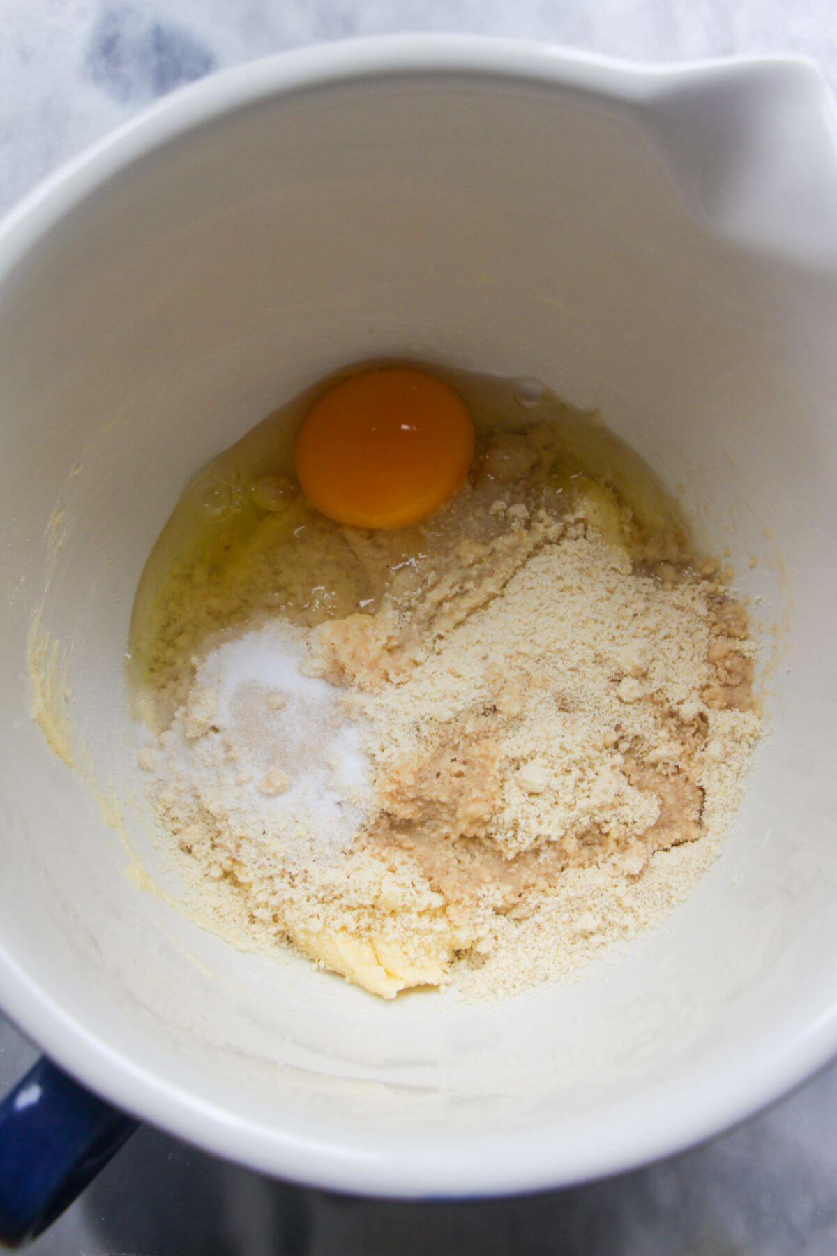 An egg, almon flour and salt in a bowl with butter and sugar.
