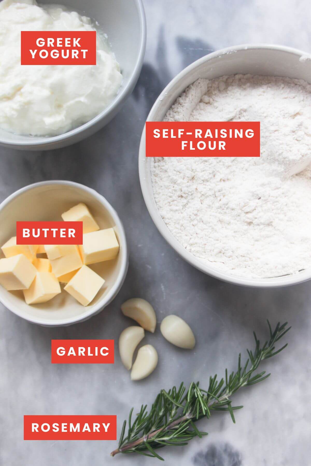 Ingredients for garlic butter dinner rolls laid out on a grey marble background and labelled.