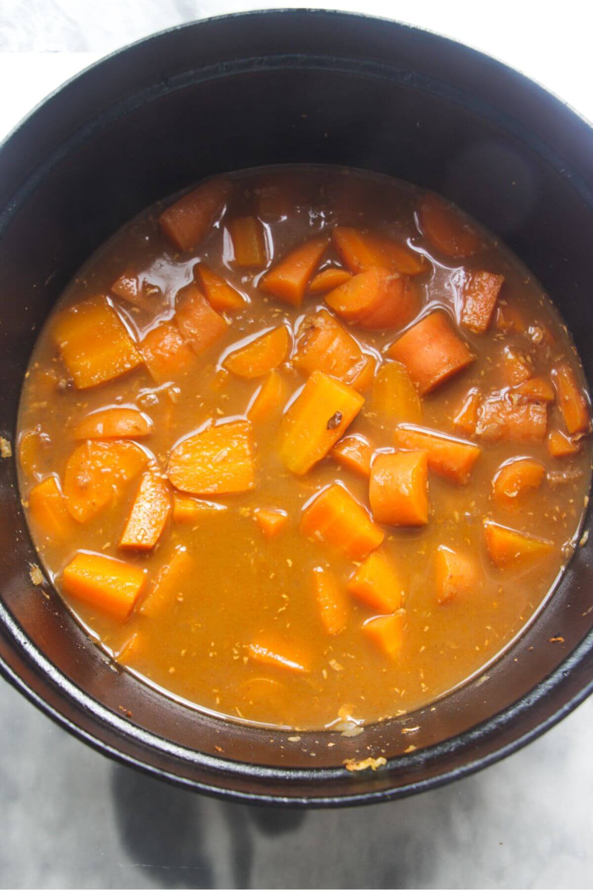 Carrots, stock and seasoning in a large black pot after being simmered.