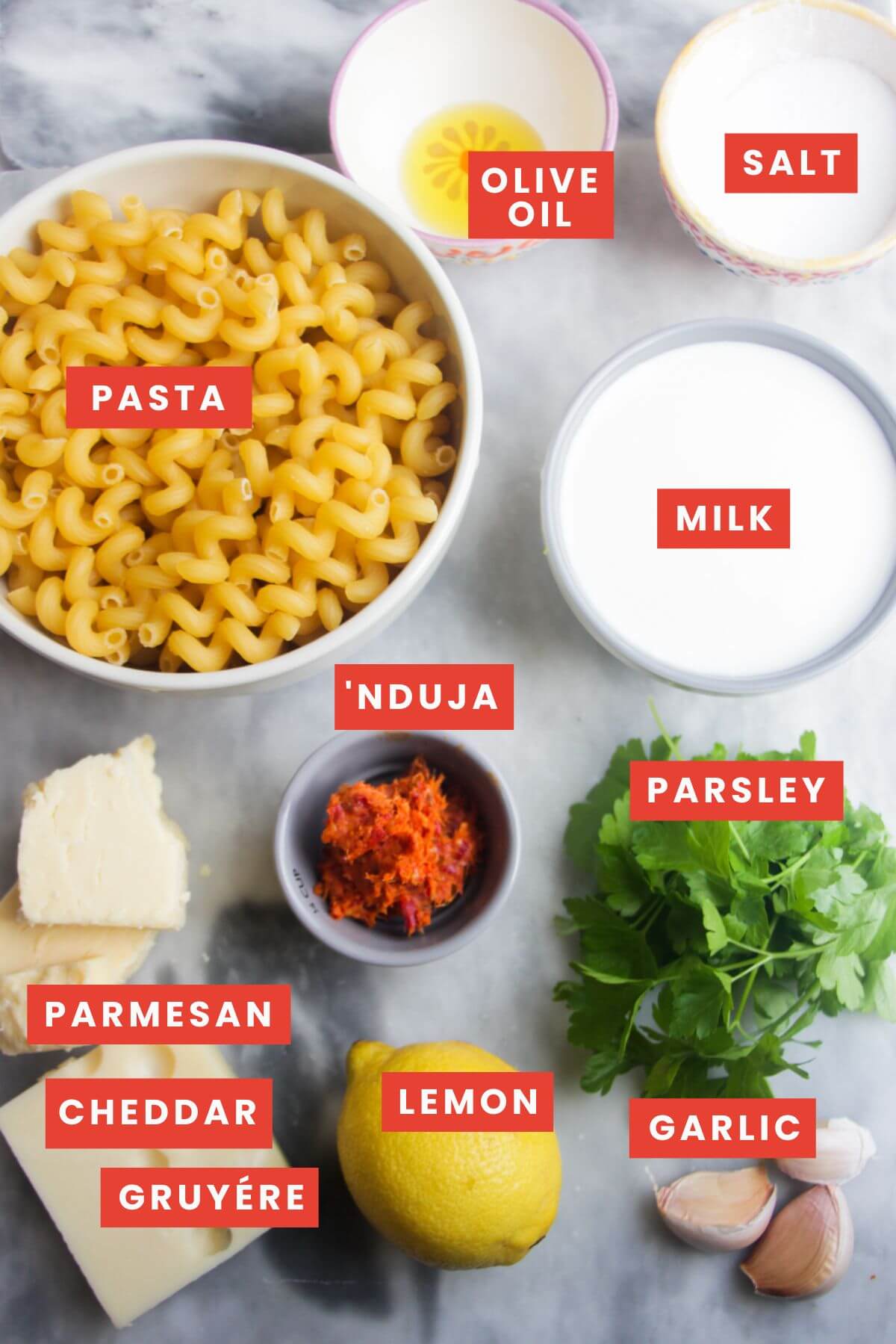 Ingredients for spicy mac and cheese laid out on a grey marble background and labelled.