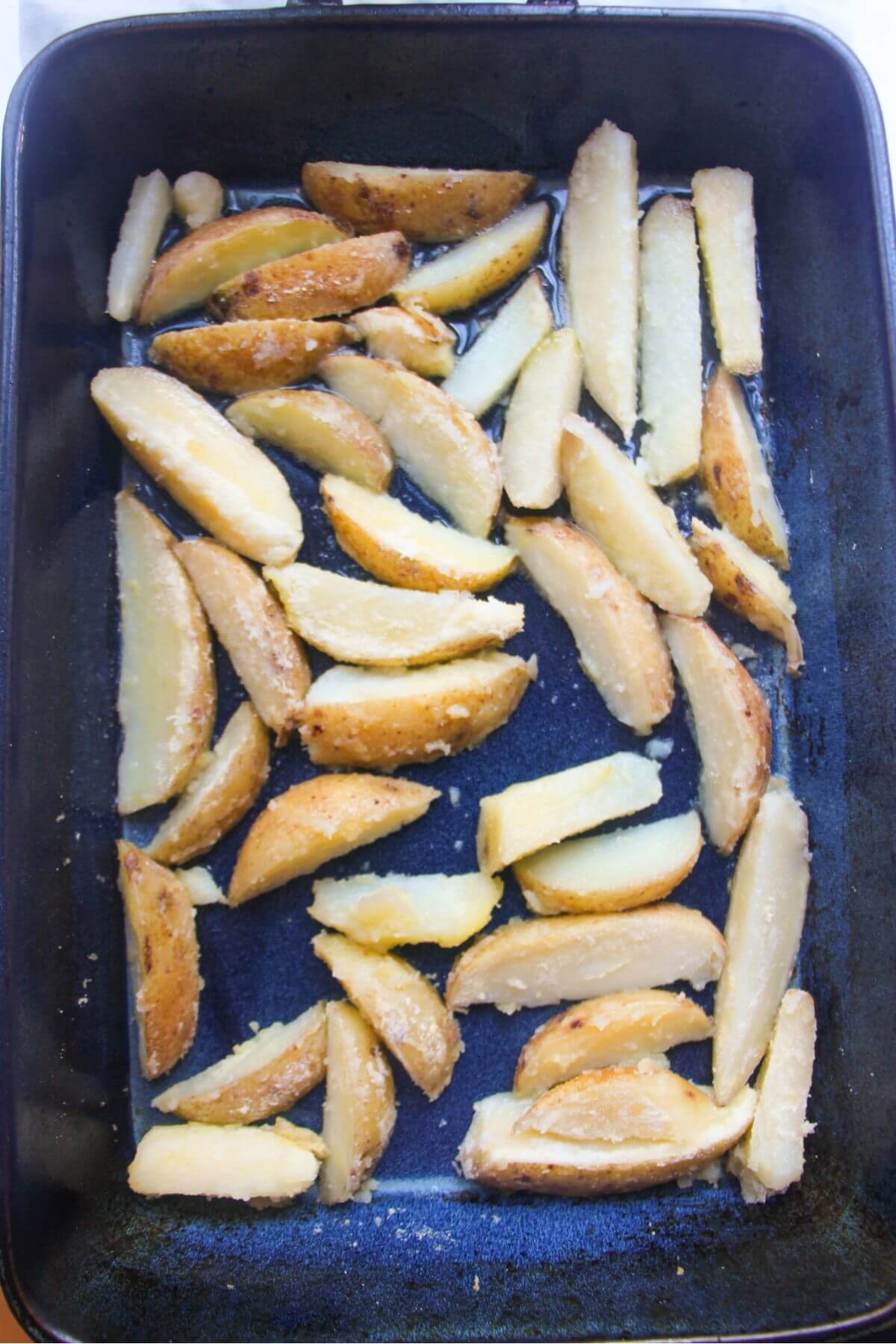 Parboiled wedges in a large blue oven dish.