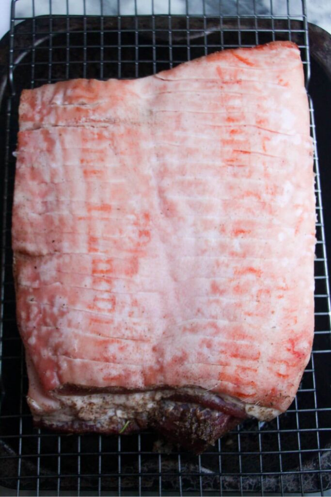 Brined pork belly on a wire rack ready to be cooked.